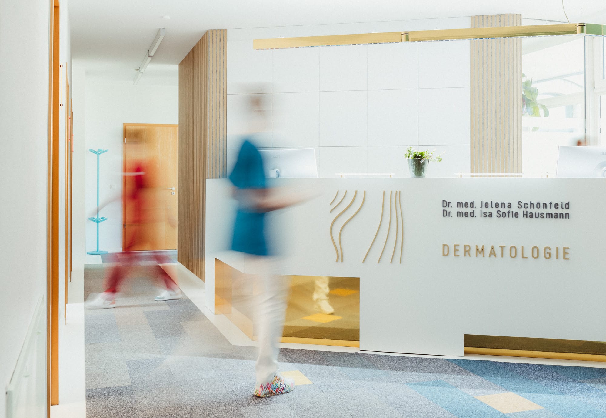 Hautarztpraxis Schönfeld & Hausmann. Eine Schwester läuft am Tresen vorbei 